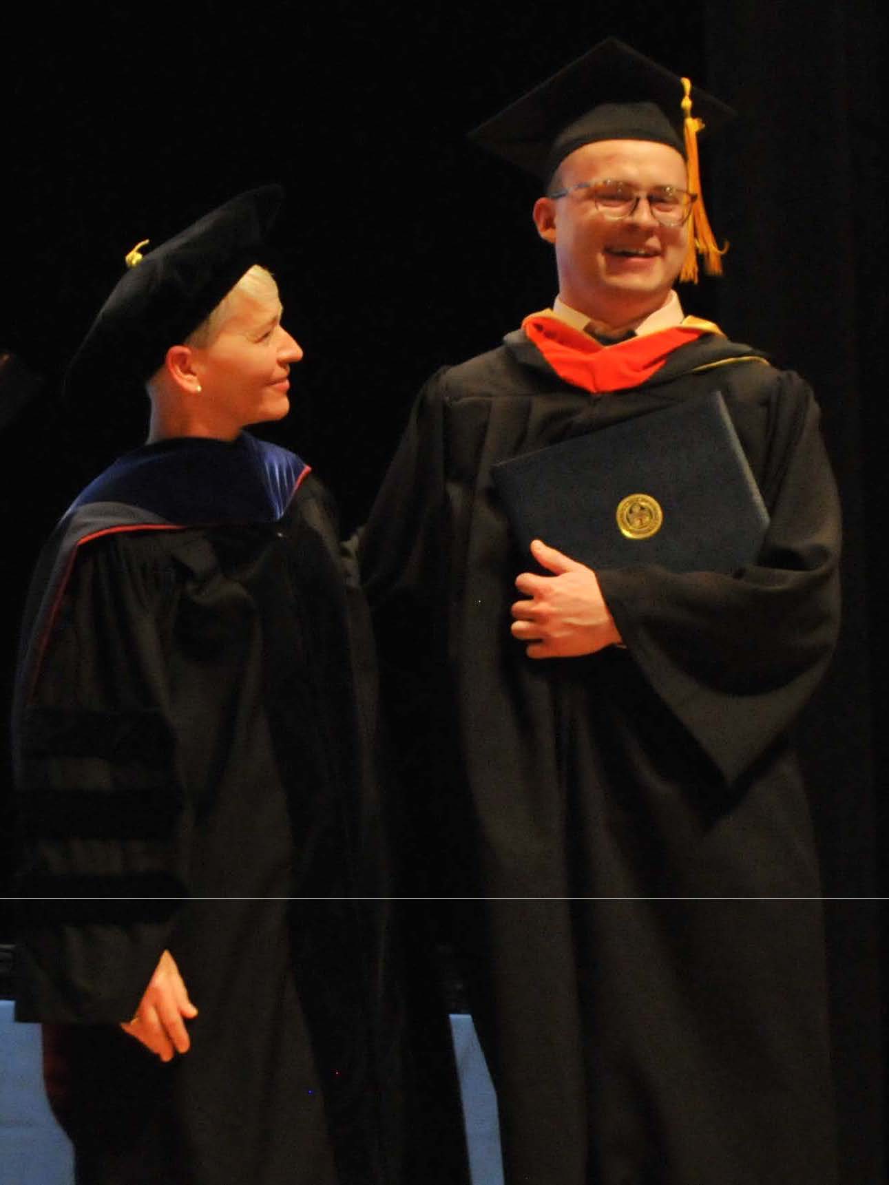 student and faculty posing w/ diploma