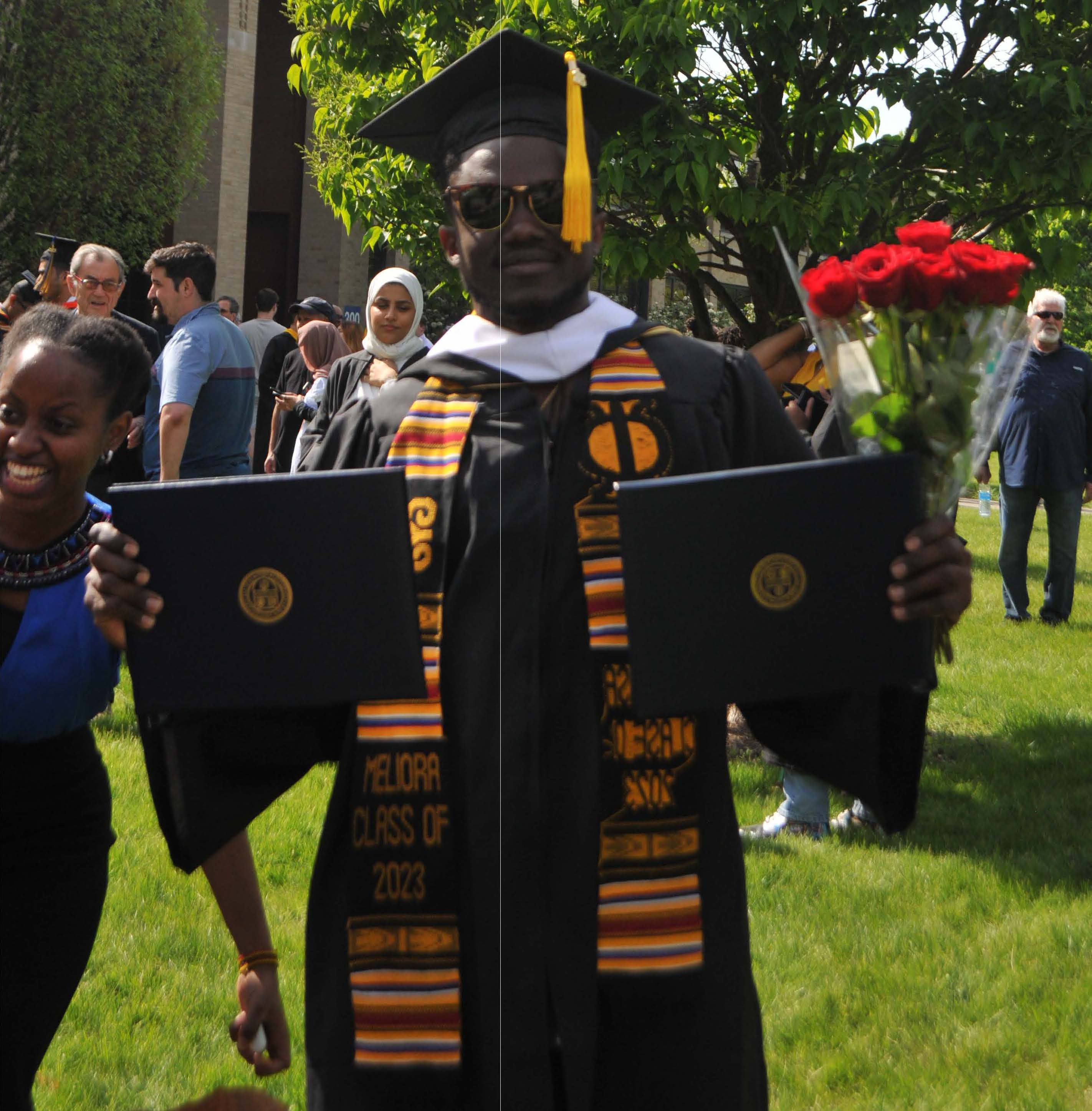 student posing w/ diplomas